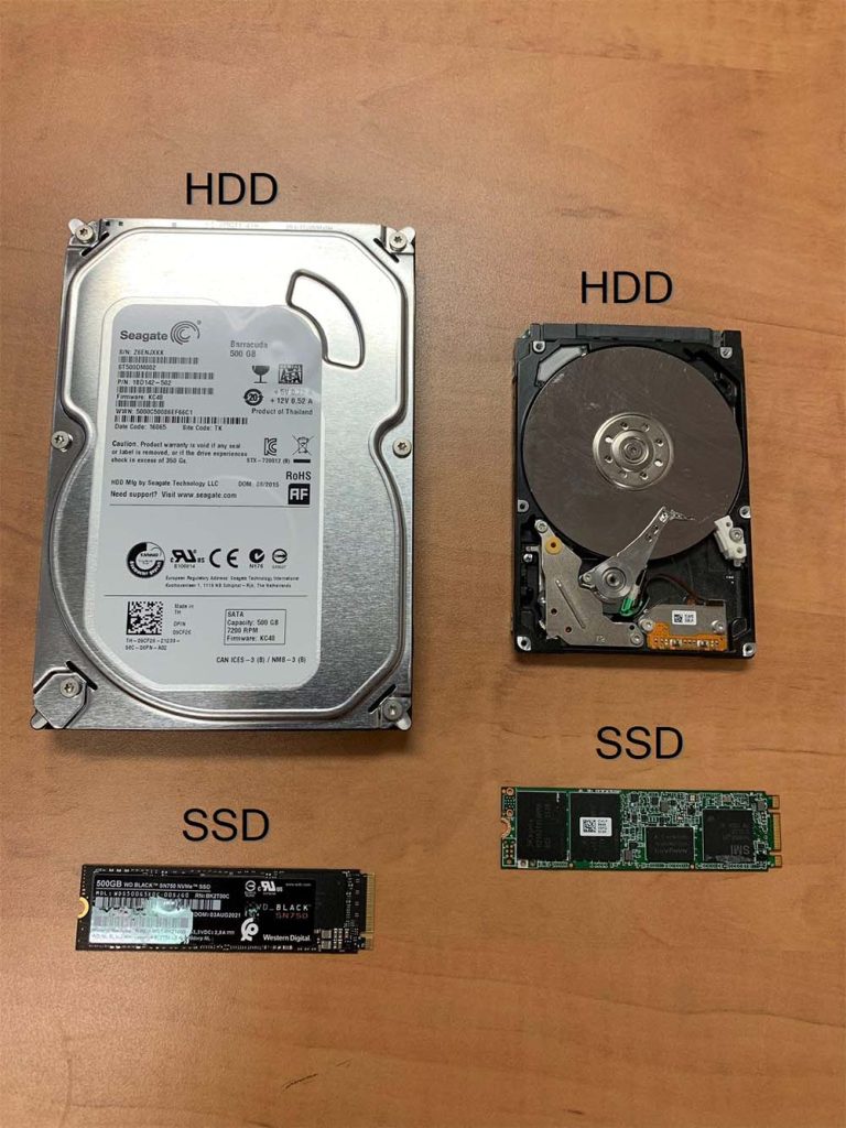 A photograph of 4 different hard drives: 2 HDDs and 2 SSDs, on a wood background.