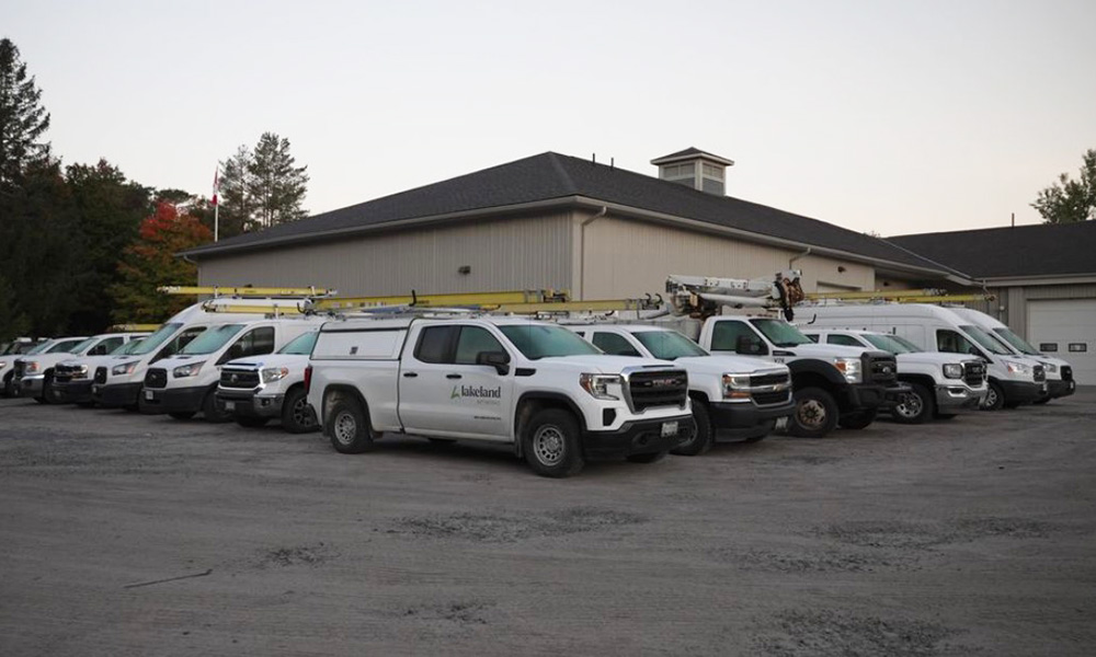 a fleet of Lakeland Networks vehicles parked behind the office