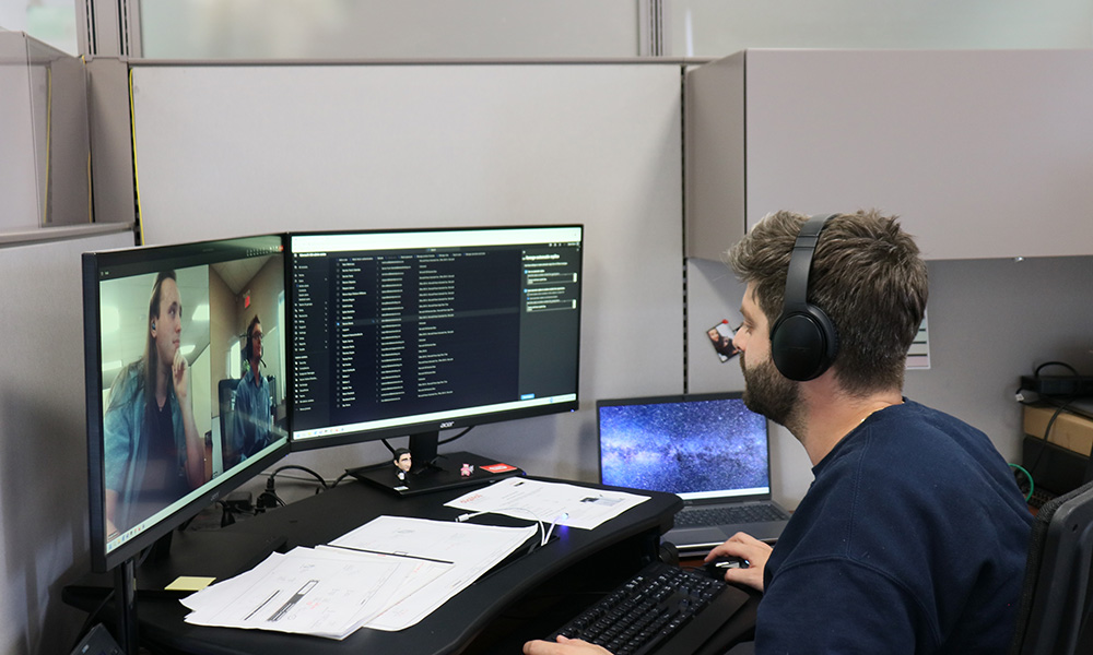 Employee in office looking at 3 screens.