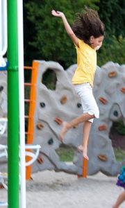 Young Sara jumping in a playground