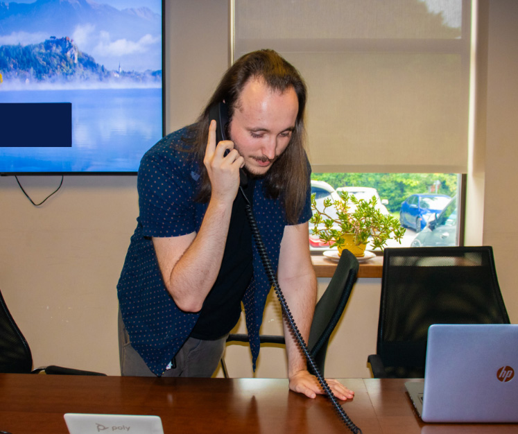 Lakeland Networks employee leaning over desk and holding landline phone to ear.