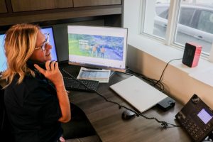 Lakeland Networks team member smiling in her office on the phone looking out the window with her computer monitors to her left.