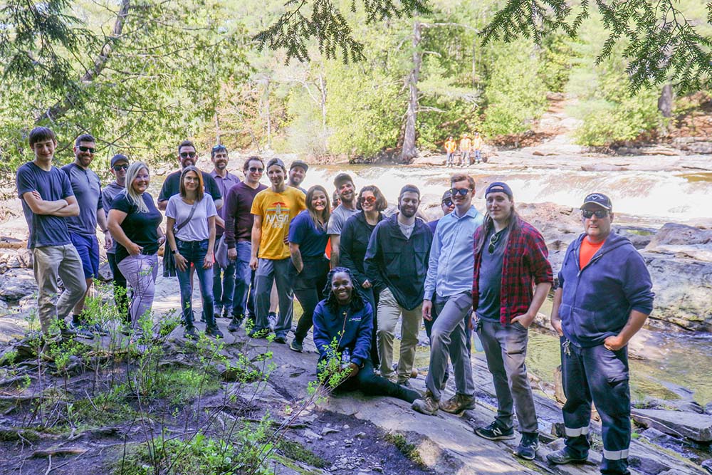 Lakeland team outside posing together in front of a waterfall.