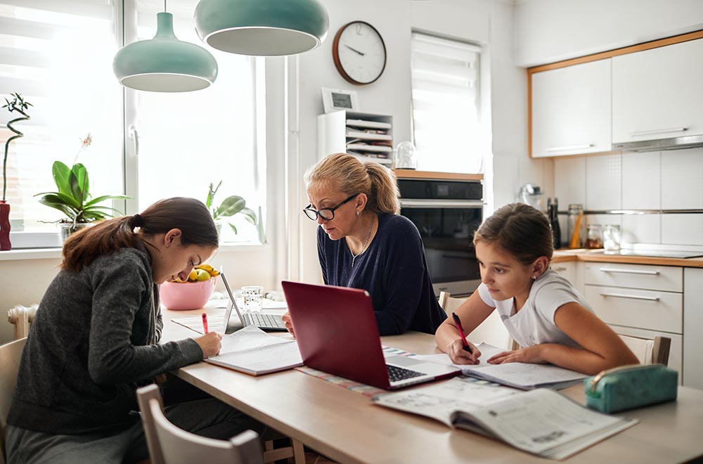 A mom and two daughters work at a kitchen table